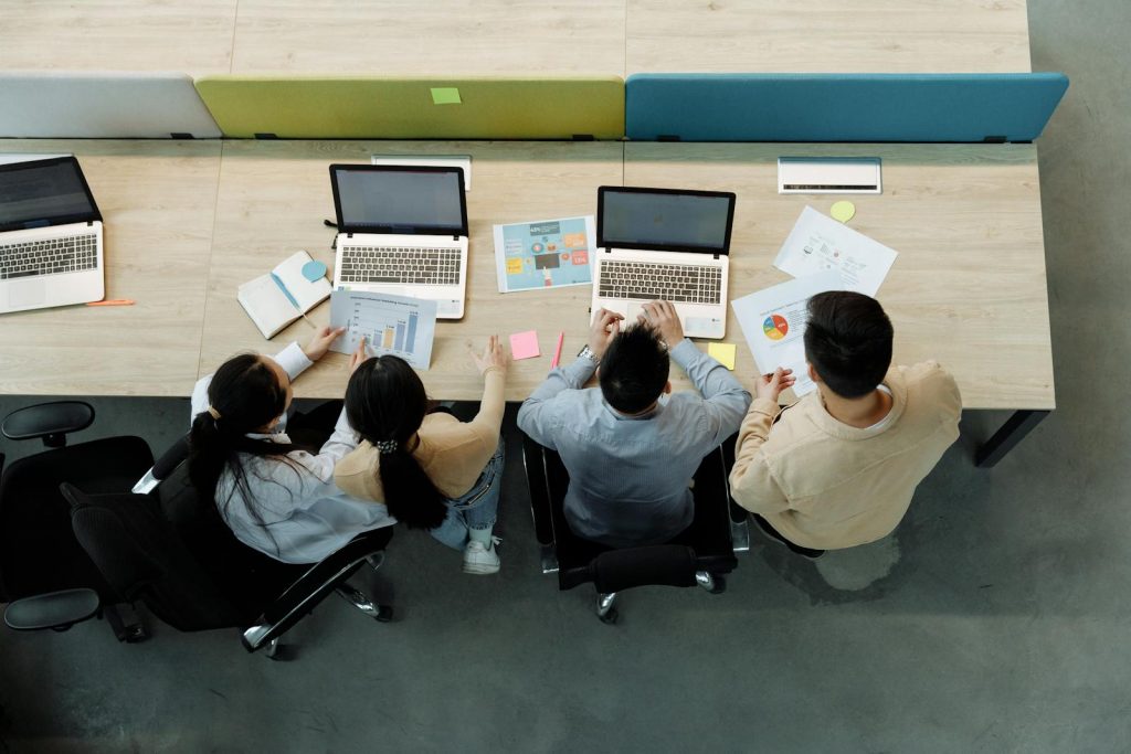Vue aérienne d'une équipe collaborant sur laptops, agence web pour PME et ETI