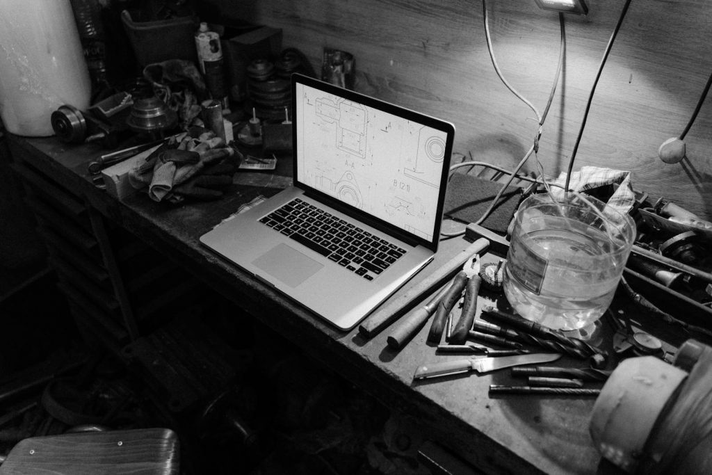 Atelier artisanal avec laptop affichant des plans, artisan digitalisé